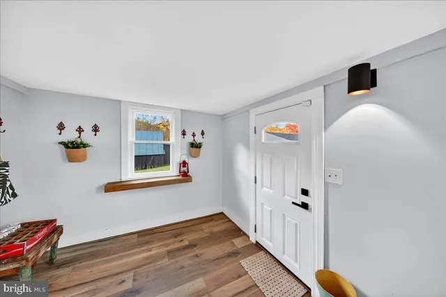 a view of a dining room with furniture a chandelier large windows and wooden floor