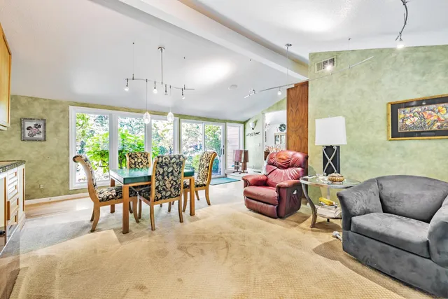 a dining room with furniture a chandelier and a large window