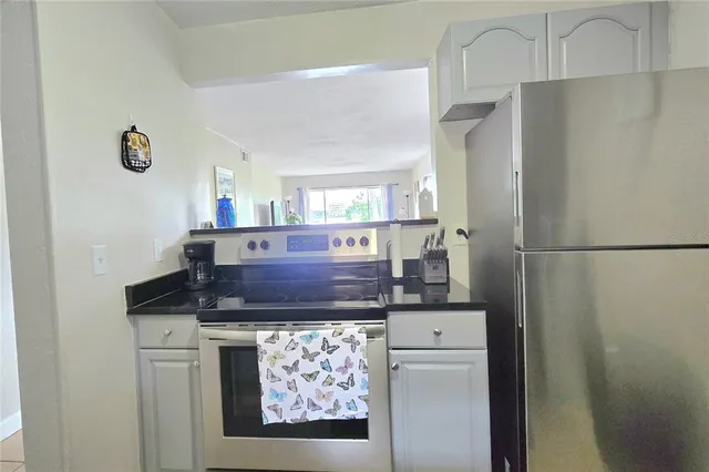 a kitchen with stainless steel appliances granite countertop a refrigerator a stove and a sink