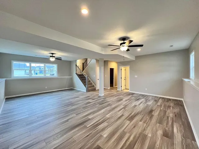 a view of a livingroom with wooden floor a ceiling fan and windows