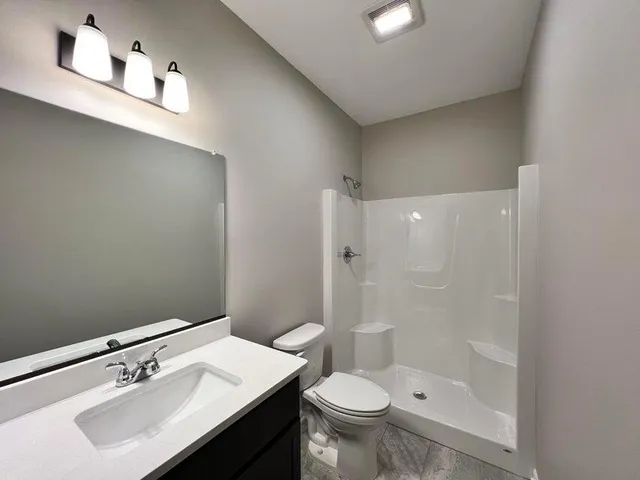 a bathroom with a sink a toilet and shower