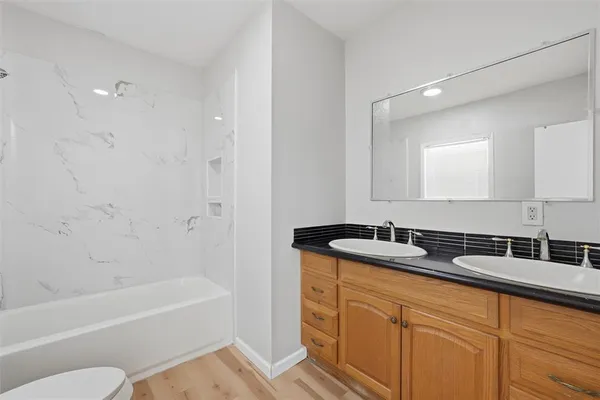 a bathroom with a granite countertop sink a mirror a bathtub and shower