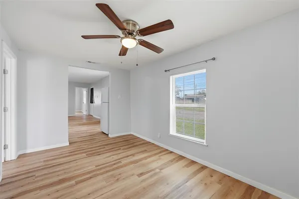 a view of an empty room with wooden floor and a window