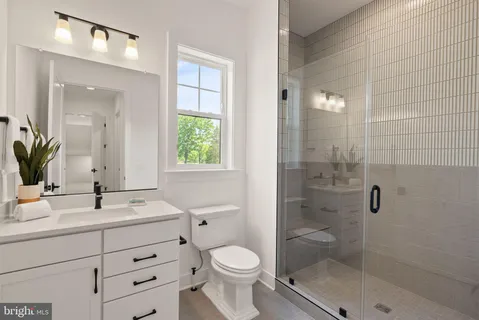 a bathroom with a granite countertop toilet sink shower and mirror