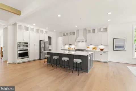 a open kitchen with stainless steel appliances kitchen island granite countertop a table chairs and a refrigerator