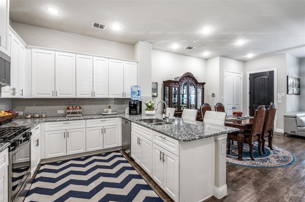 1560 Windermere Way Dallas, TX 75234 - Photo 11 of 25 Kitchen featuring a kitchen breakfast bar, a peninsula, white cabinetry, and recessed lighting