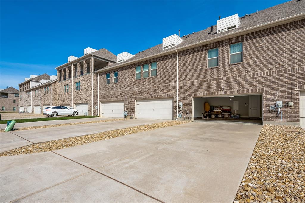 1560 Windermere Way Dallas, TX 75234 - Photo 24 of 25 View of side of property with brick siding, a garage, concrete driveway, and a residential view