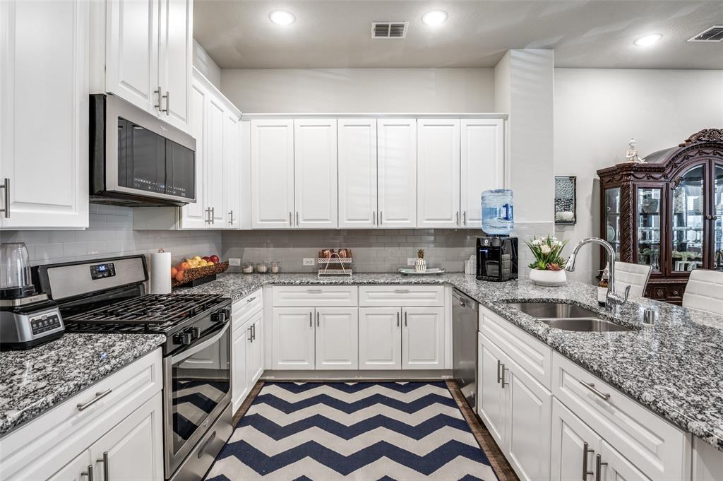 1560 Windermere Way Dallas, TX 75234 - Photo 10 of 25 Kitchen with stainless steel appliances, light stone counters, white cabinets, recessed lighting, and a peninsula