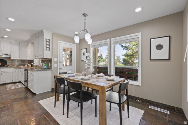 2370 Quail Run Circle East Sandy, UT 84093 - Photo 11 of 54 Dining area featuring a natural wood table, a multi-light chandelier, and three large windows