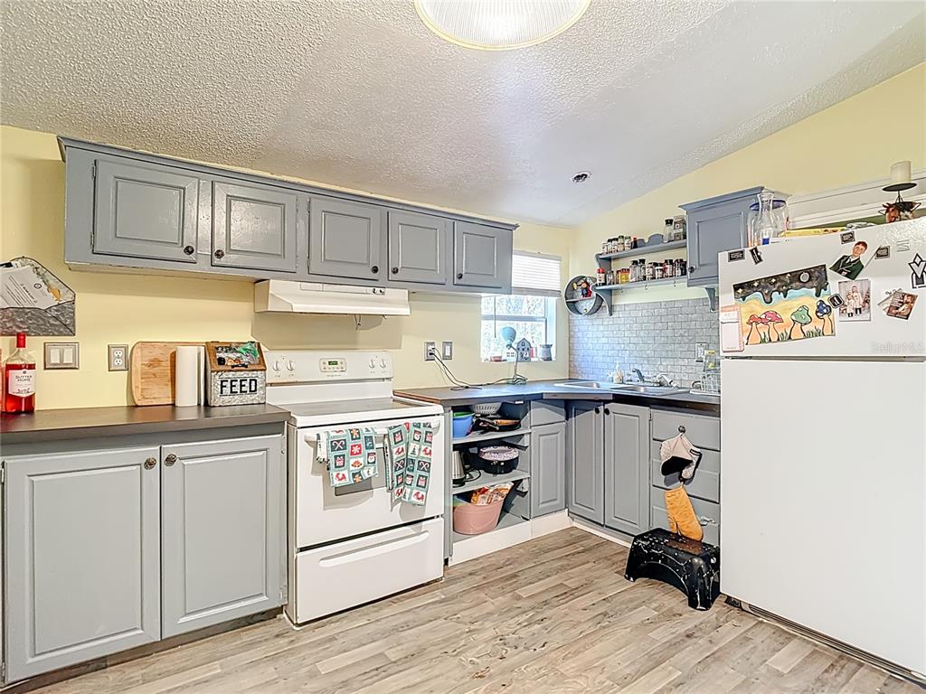 6421 Sunnyside Ranch Road Brooksville, FL 34602 - Photo 21 of 49 a kitchen with stainless steel appliances granite countertop a stove a sink dishwasher and white cabinets with wooden floor