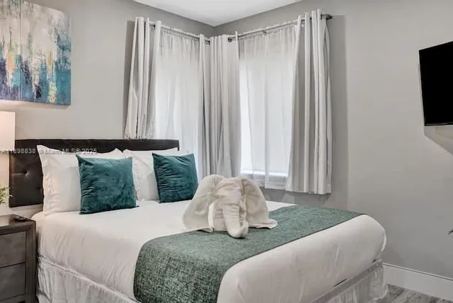 a bedroom with a bed and flat tv screen on a dresser