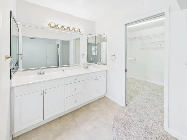 a spacious bathroom with a double vanity sink a mirror and a shower