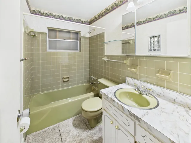 a bathroom with a granite countertop toilet sink and mirror