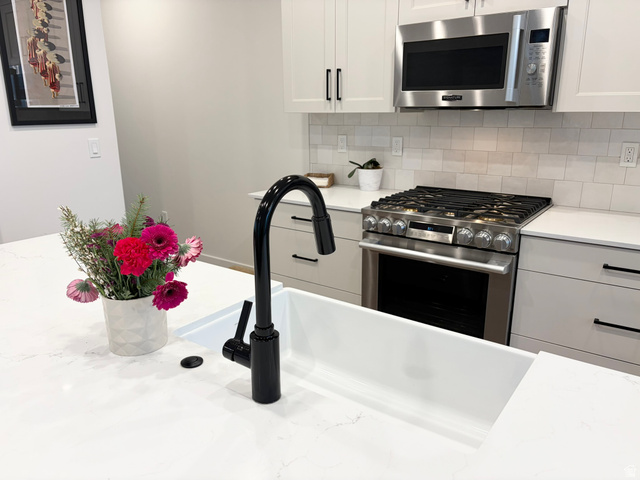 545 East 7215 South Midvale, UT 84047 - Photo 7 of 27 Kitchen featuring stainless steel appliances, white cabinetry, tasteful backsplash, and light stone counters