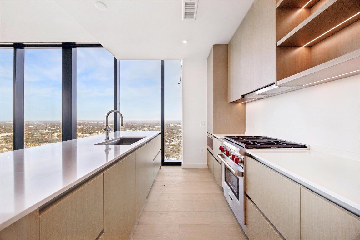 610 Davis Street, Unit 5007 Austin, TX 78701 - Photo 2 of 33 Kitchen featuring designer range, floor to ceiling windows, open shelves, recessed lighting, and cream cabinets