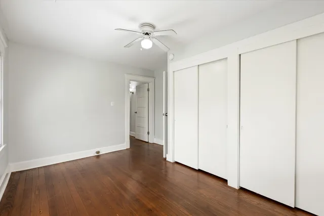 an empty room with wooden floor and fan