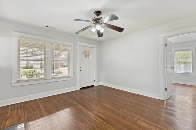 a view of an empty room with wooden floor and a window