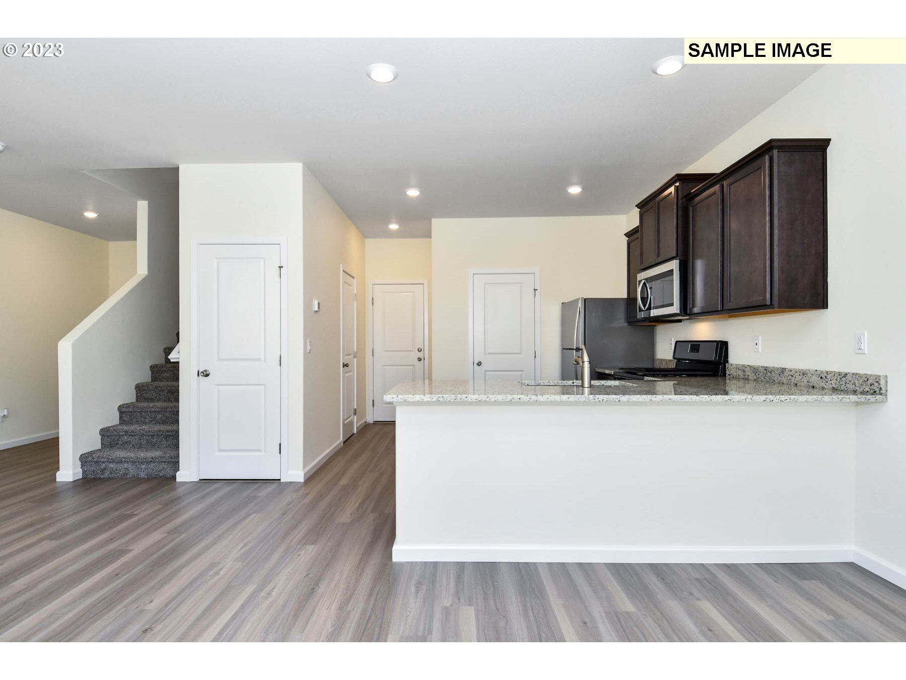 3974 Southwest Knapp Drive Gresham, OR 97080 - Photo 13 of 14 a living room with stainless steel appliances kitchen island granite countertop a refrigerator a stove a sink and a microwave with wooden floor