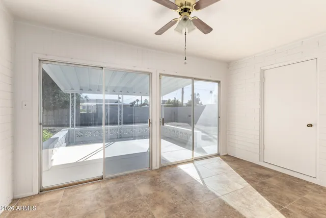 an empty room with a window and ceiling fan