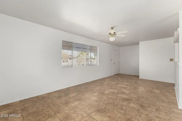 an empty room with windows and fan