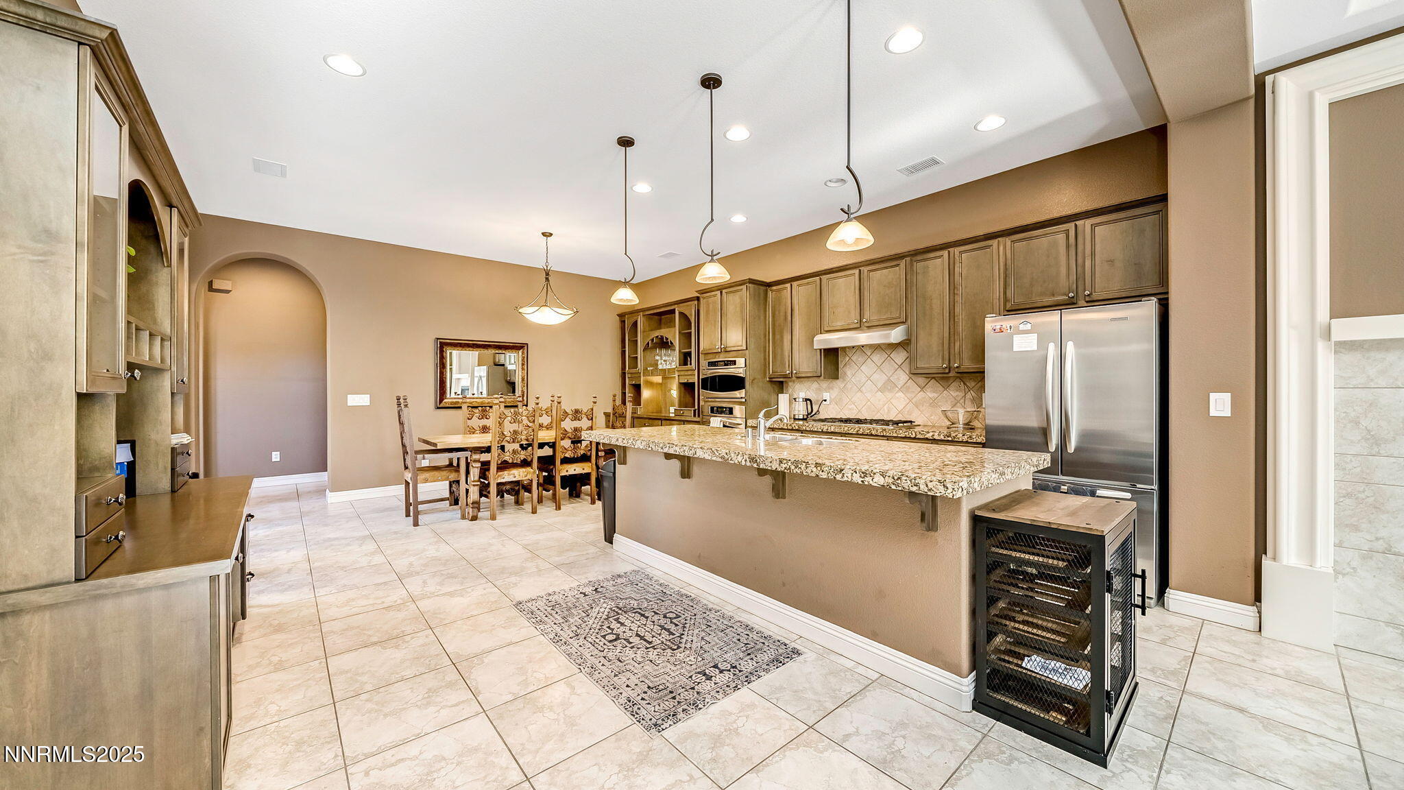 1812 Braemore Drive Reno, NV 89521 - Photo 8 of 26 a kitchen with stainless steel appliances kitchen island granite countertop a refrigerator oven a sink a dining table and chairs with wooden floor