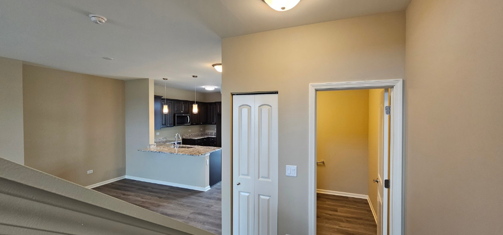 249 Timber Ridge Court Joliet, IL 60431 - Photo 8 of 25 a view of a hallway with wooden floor and a kitchen