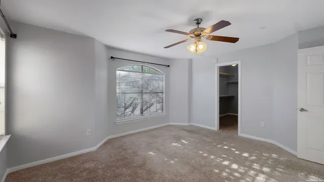 an empty room with windows and fan