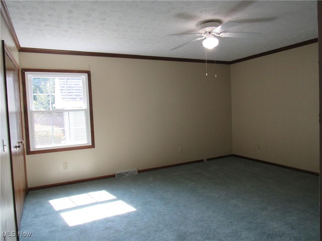 1120 Vincent Road Southeast North Canton, OH 44720 - Photo 33 of 50 Owner's suite featuring new carpet, a textured ceiling, and ceiling fan