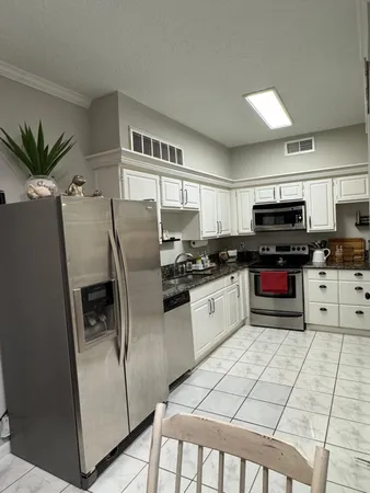 a kitchen with granite countertop a refrigerator a sink a stove a microwave and cabinets