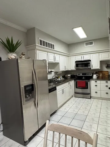 a kitchen with granite countertop a refrigerator a sink a stove a microwave and cabinets