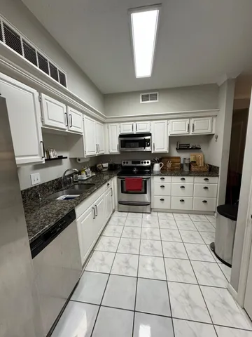 a kitchen with stainless steel appliances granite countertop a stove top oven a sink a counter space and cabinets
