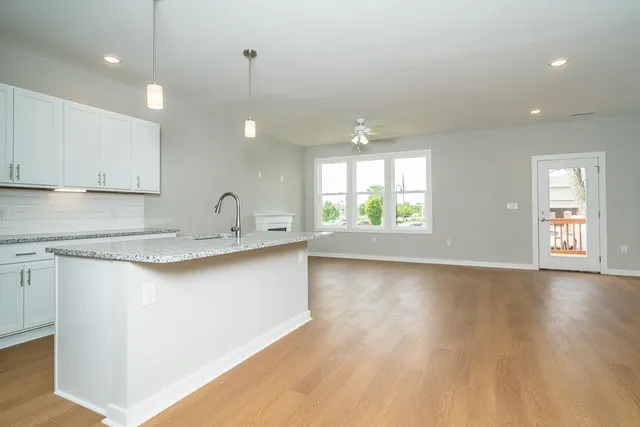 a kitchen with stainless steel appliances granite countertop a sink a stove and a wooden floors