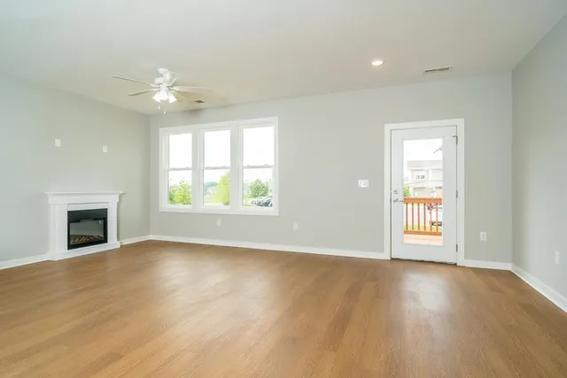 an empty room with windows fireplace and wooden floor