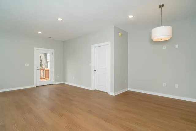 a view of an empty room with wooden floor and windows