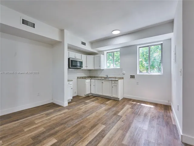 a view of a kitchen with wooden floor and a window
