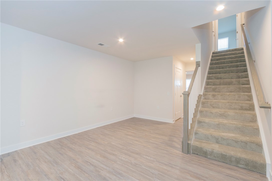 233 Scenic Road Anderson, SC 29621 - Photo 10 of 50 A well-lit area with wood plank flooring and a carpeted staircase leading to the upper level.