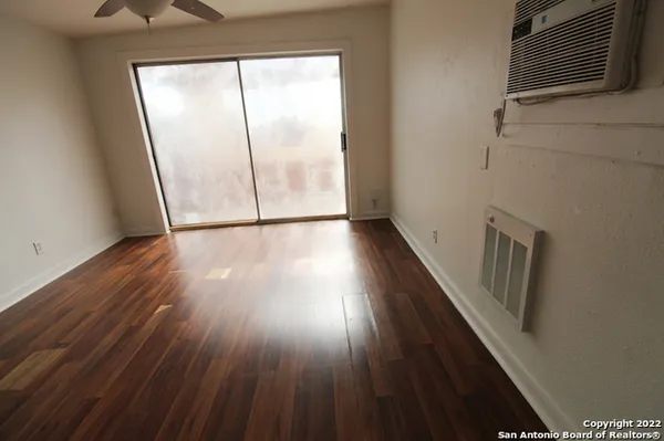 an empty room with wooden floor fan and windows