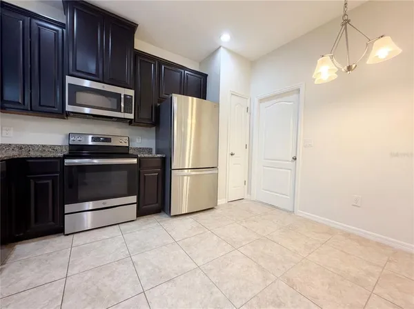 a kitchen with granite countertop a refrigerator and a stove top oven