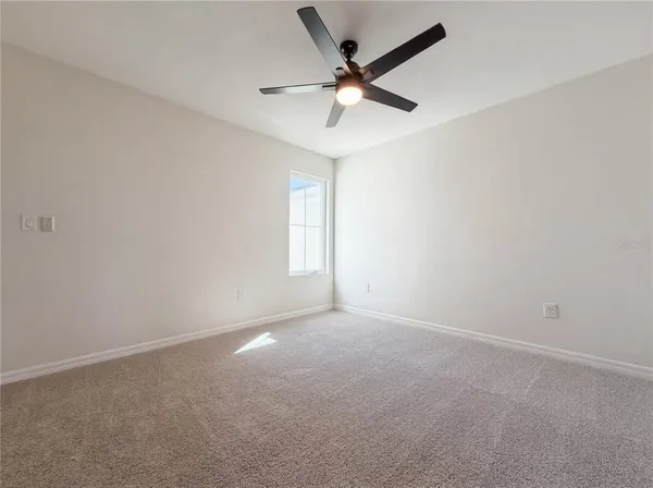 an empty room with a window and a fan