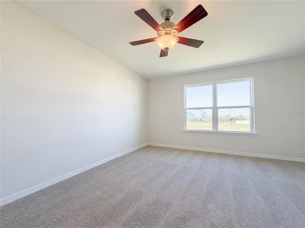 an empty room with a window and a ceiling fan