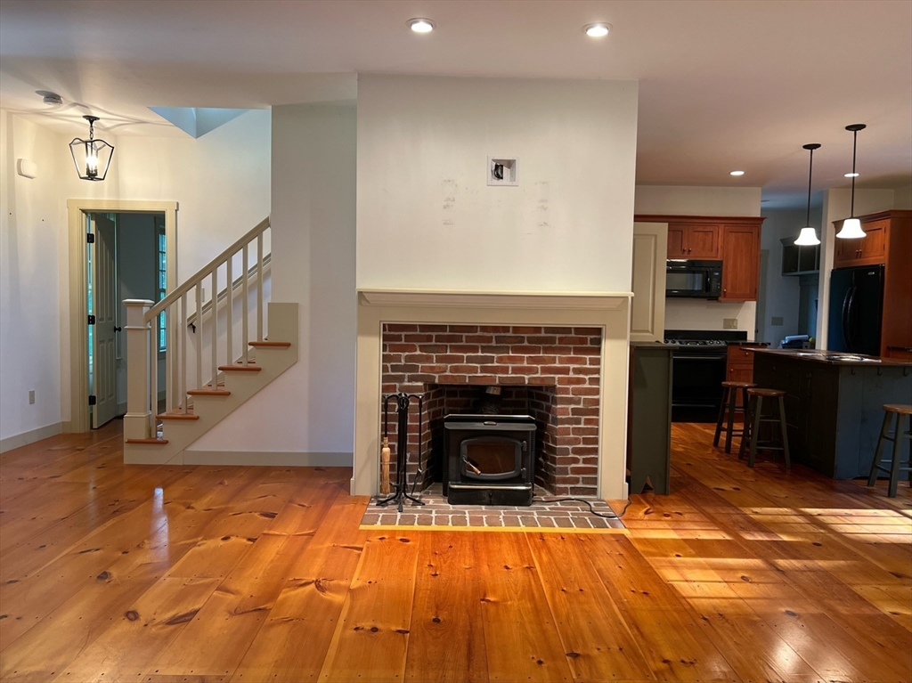 160 Quaker Street Northbridge, MA 01534 - Photo 6 of 36 a view of an empty room with wooden floor fire place and kitchen view