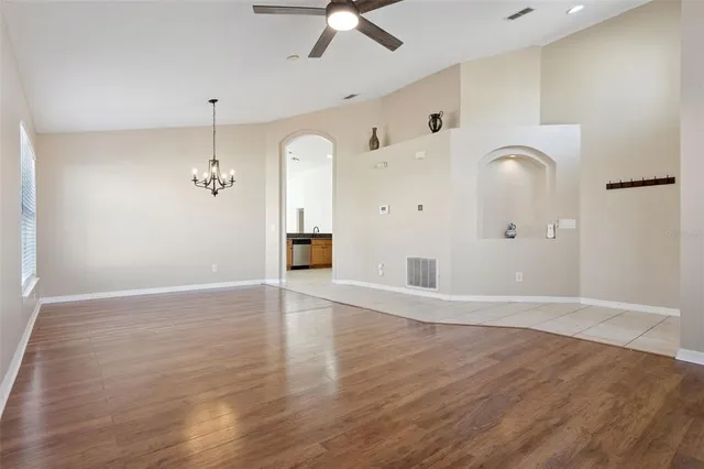 a view of an empty room with window and wooden floor