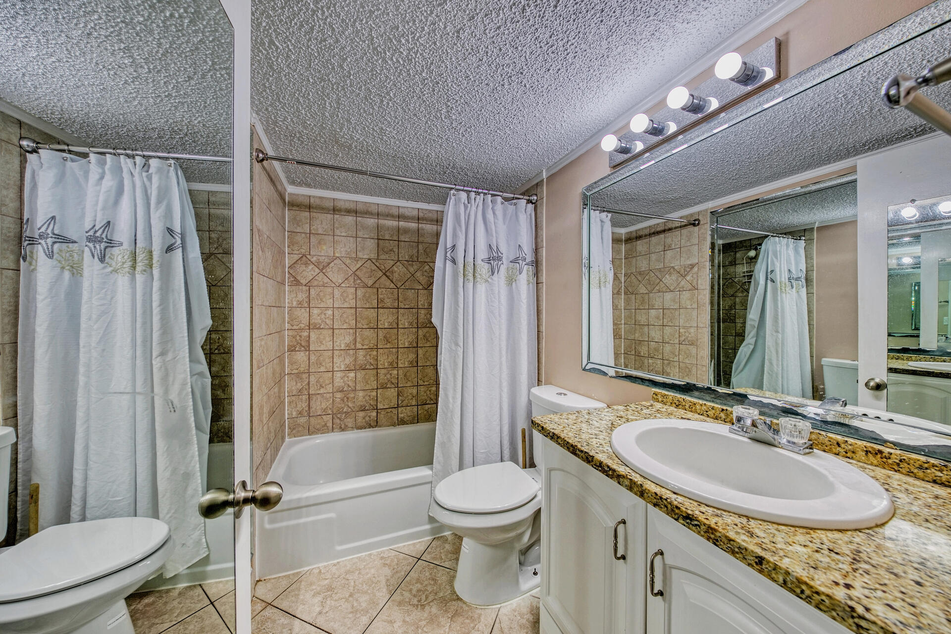 15413 Front Beach Road, Unit 505 Panama City Beach, FL 32413 - Photo 15 of 28 a bathroom with a granite countertop sink toilet mirror and shower