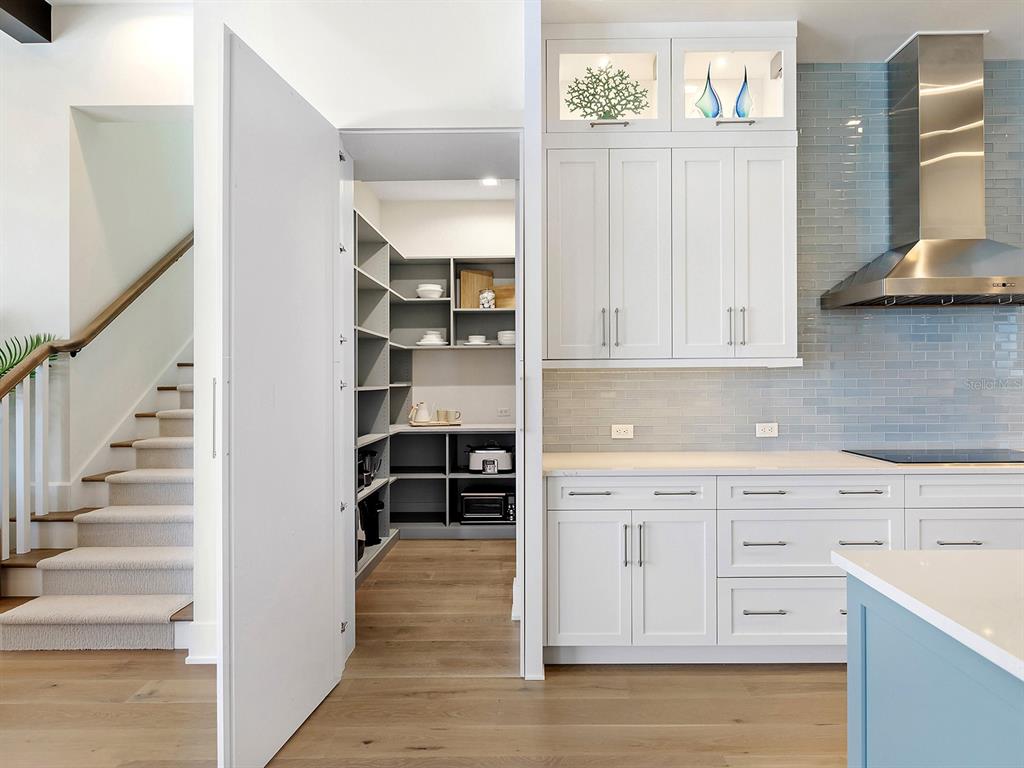 4218 Butte Trail Lakewood Ranch, FL 34211 - Photo 24 of 89 a kitchen with white cabinets and wooden floor