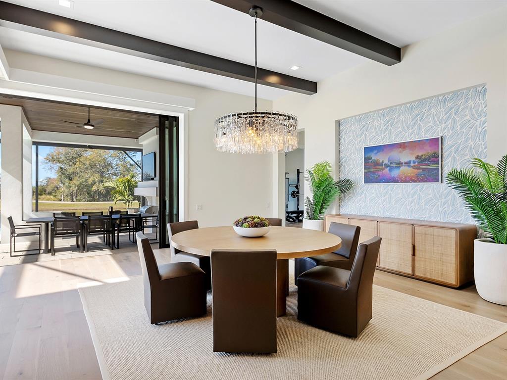 4218 Butte Trail Lakewood Ranch, FL 34211 - Photo 26 of 89 a dining room with wooden floor a chandelier a wooden table and chairs