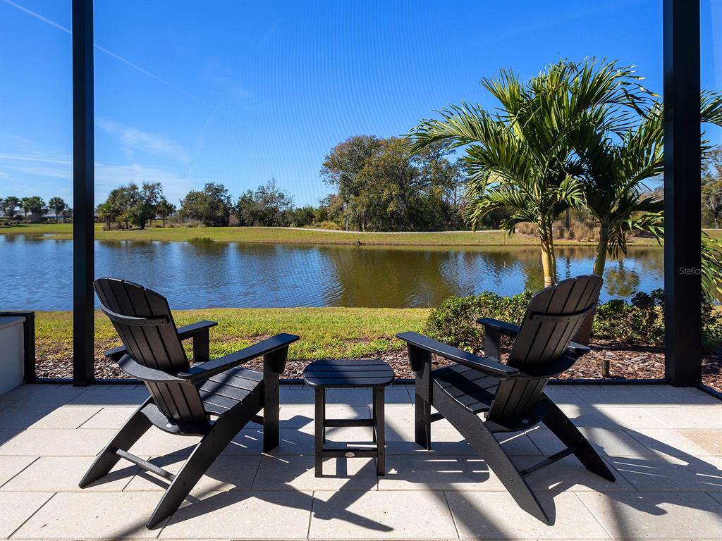 4218 Butte Trail Lakewood Ranch, FL 34211 - Photo 73 of 89 a view of a lake with table and chairs under an umbrella
