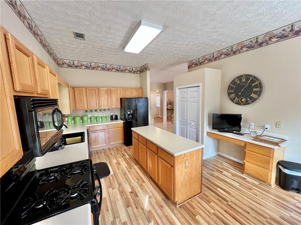 19 Meadow Crest Court Powder Springs, GA 30127 - Photo 6 of 26 a large white kitchen with a stove a sink dishwasher and a fireplace with wooden floor
