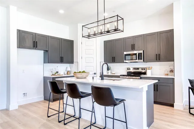 a kitchen with stainless steel appliances a sink a stove a refrigerator cabinets and a dining table