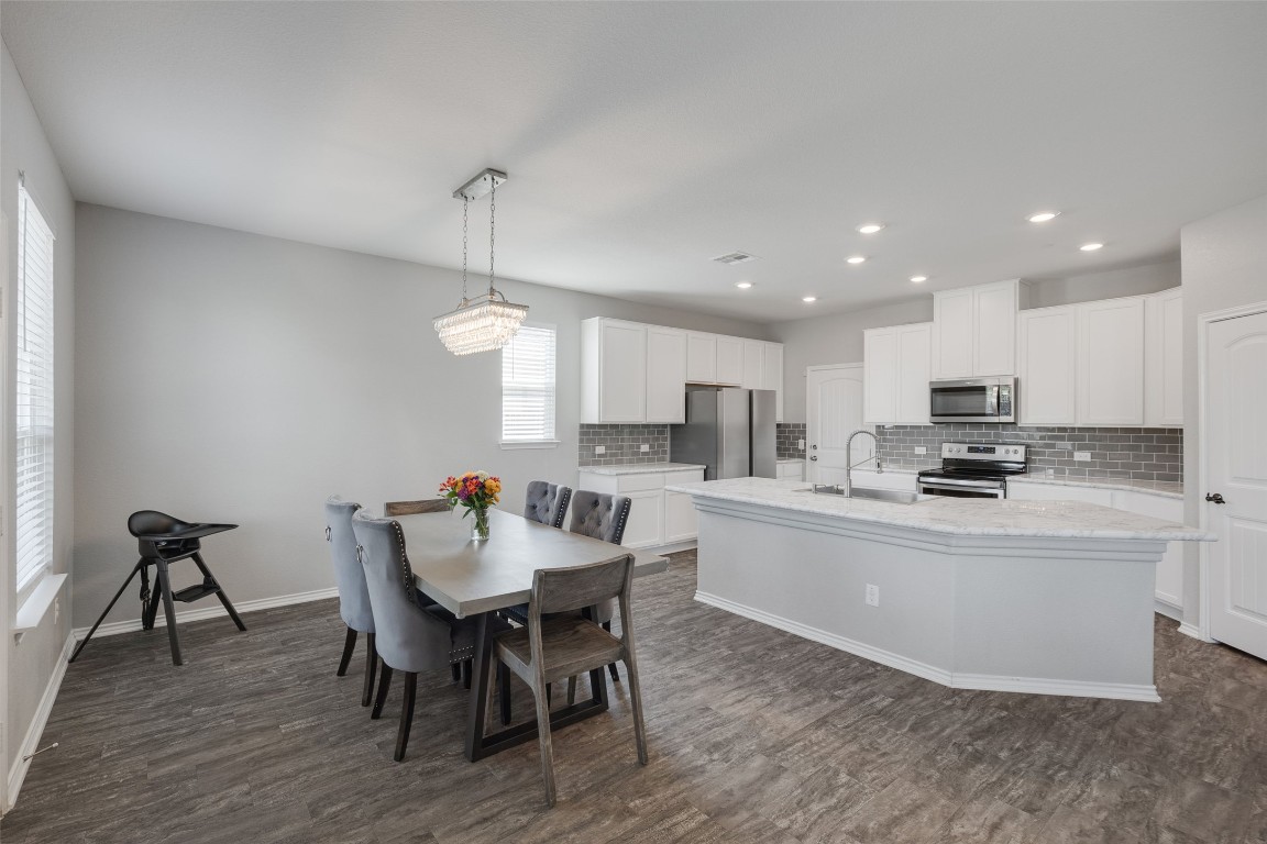 214 Saranac Drive Elgin, TX 78621 - Photo 12 of 37 a kitchen with a dining table chairs and white cabinets