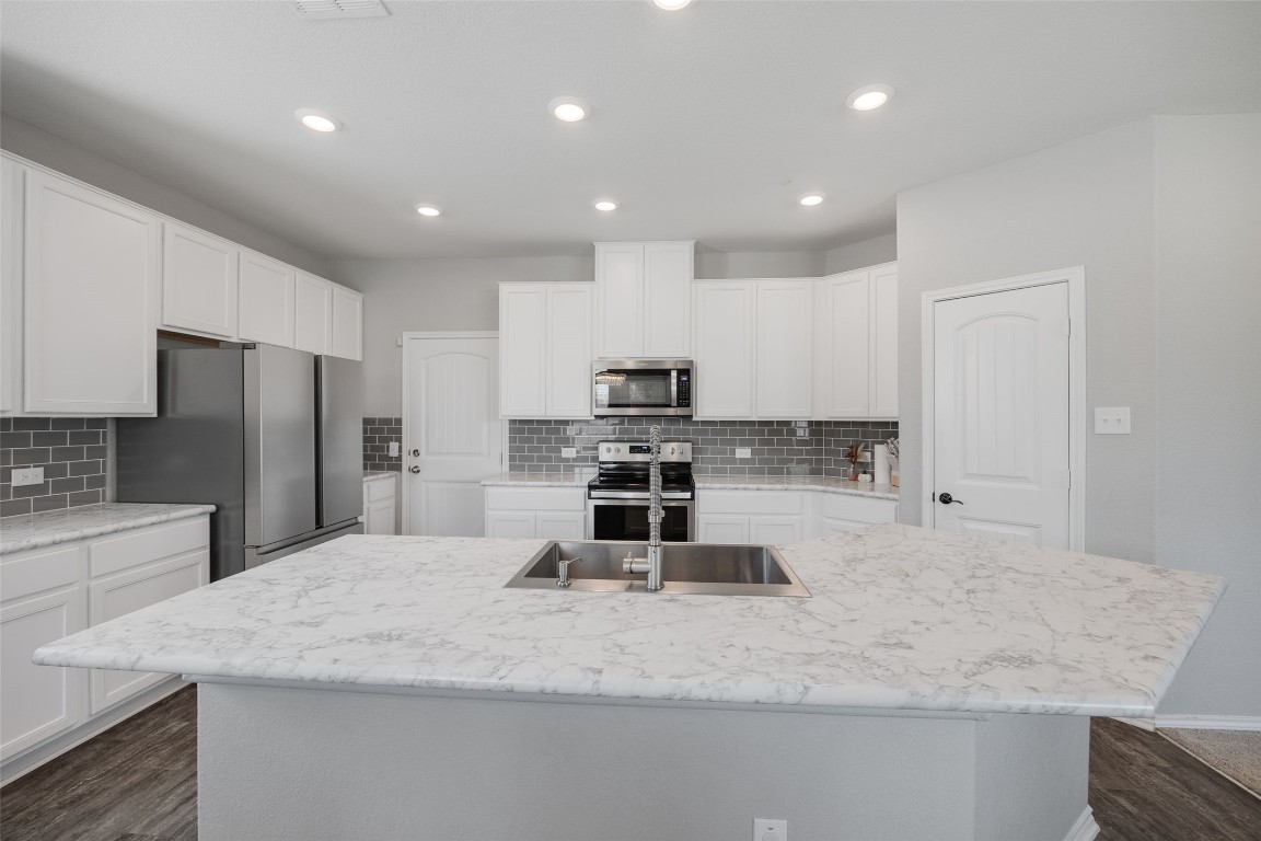 214 Saranac Drive Elgin, TX 78621 - Photo 10 of 37 a large kitchen with kitchen island a large counter top stainless steel appliances and cabinets